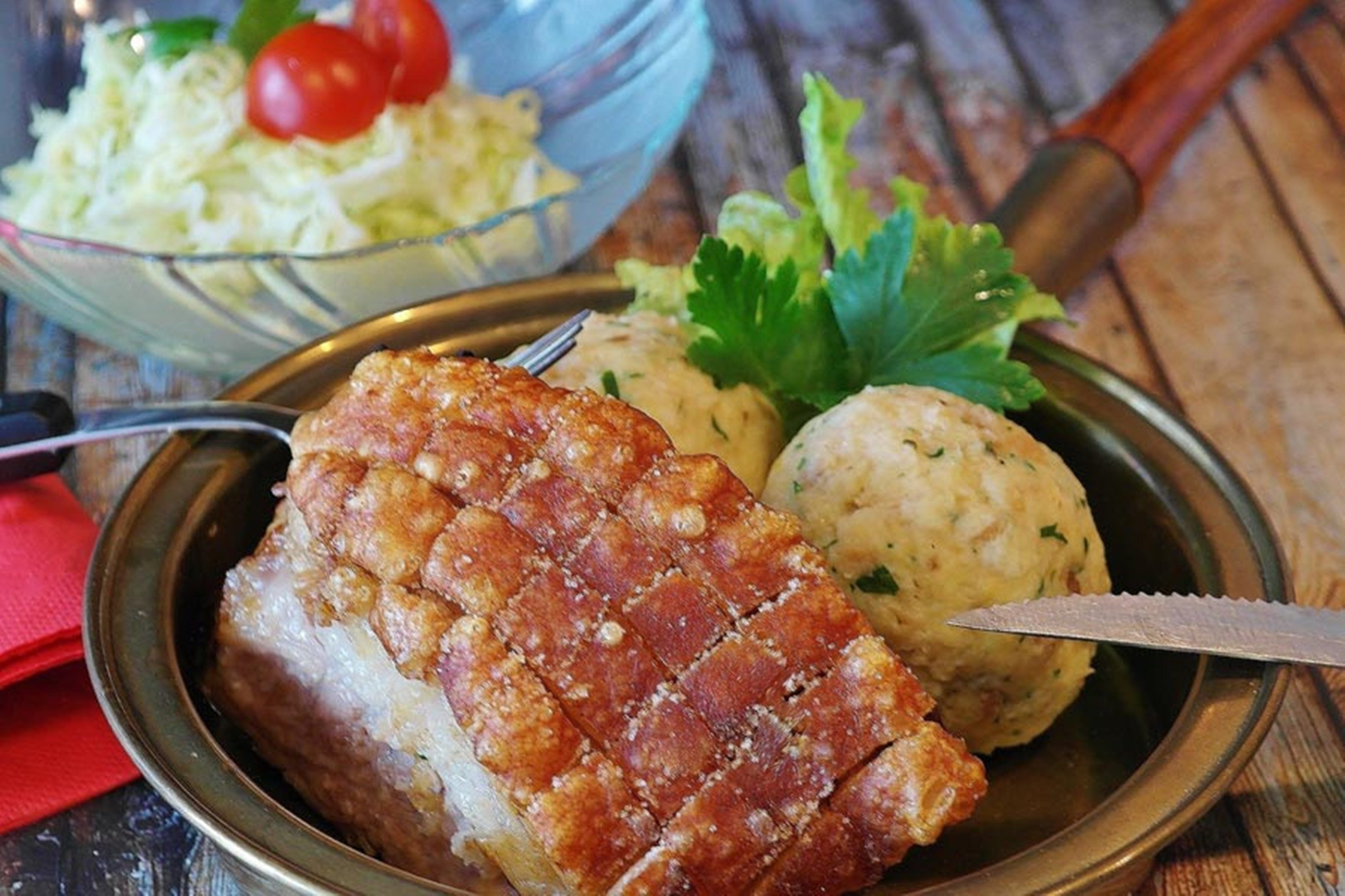 Une assiette comprenant un morceau de viande rôtie, une boulette et une salade en accompagnement.