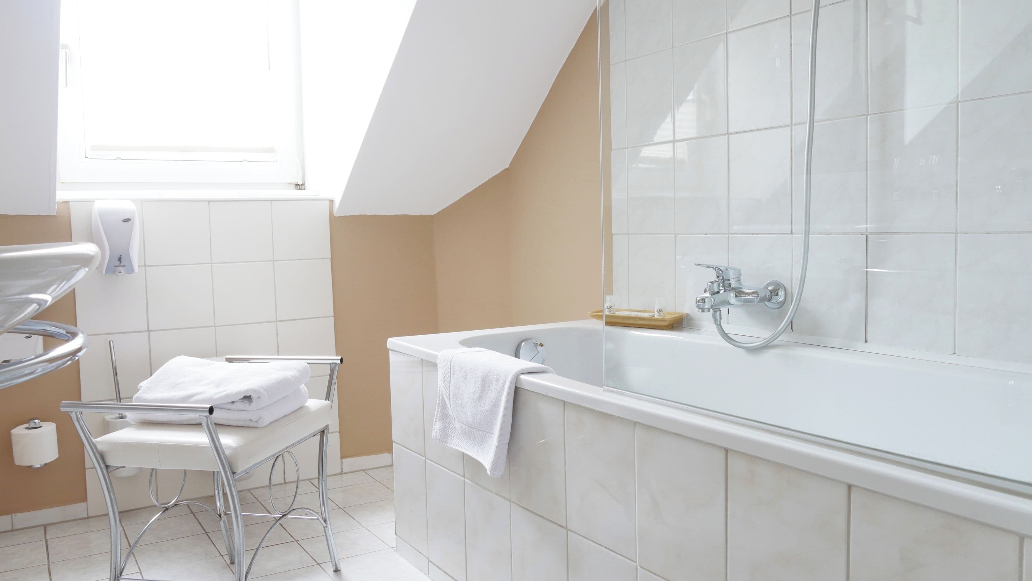 Une salle de bain moderne avec une baignoire sur pieds, un porte-serviettes et un distributeur de savon liquide.