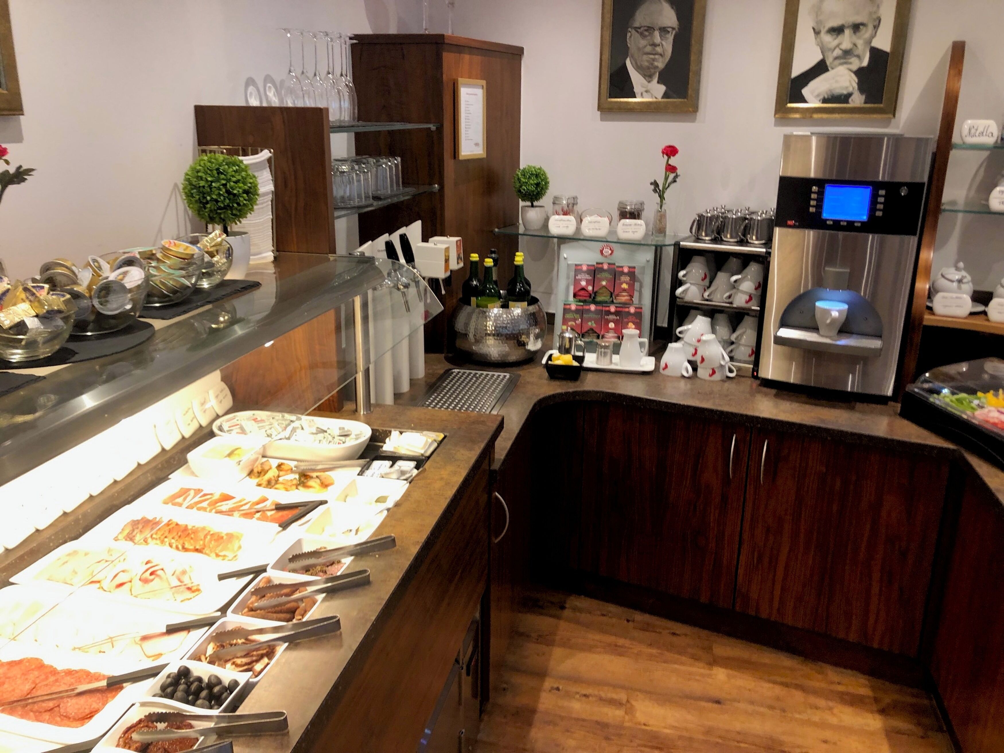 Zona de bufé con diversas opciones de comida, una máquina de café y un enfriador de vino.