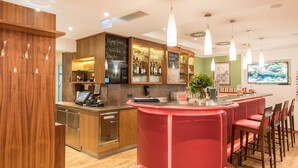 A bar area with a red bar counter, wooden cabinets, and a television screen.