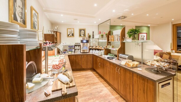 A modern kitchen with wooden cabinets, a coffee station, and various food items displayed.