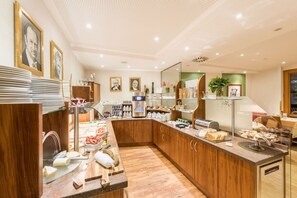 A modern kitchen with wooden cabinets, a coffee station, and various food items displayed. - Austria Classic Hotel Hölle (Salzburg)