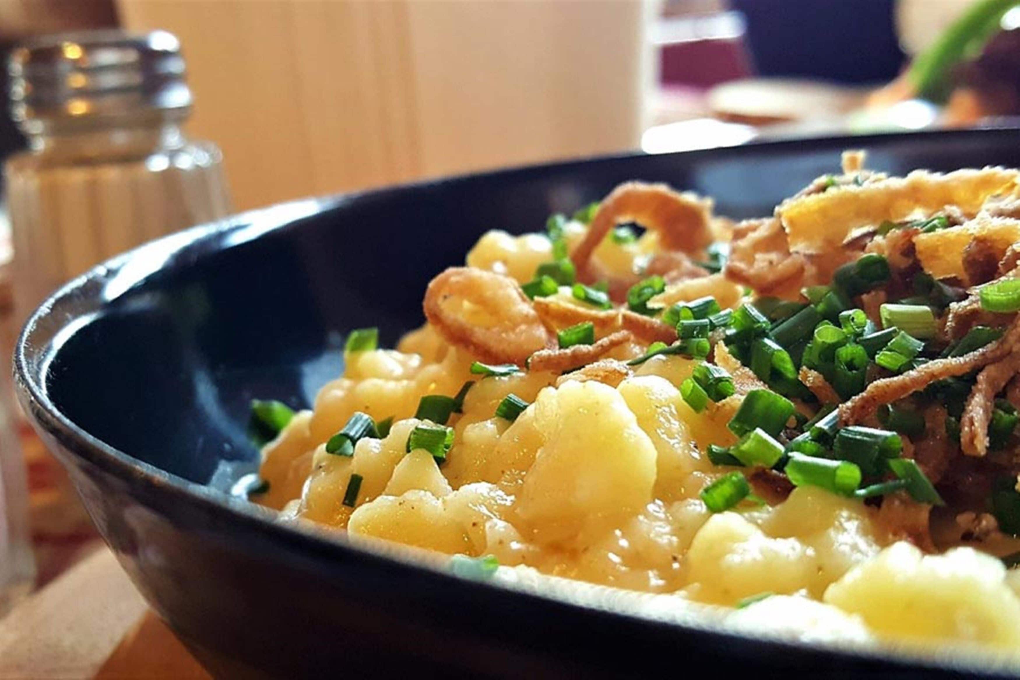 Un bol d'aliments amb ceba verda picada i ceba fregida per sobre.
