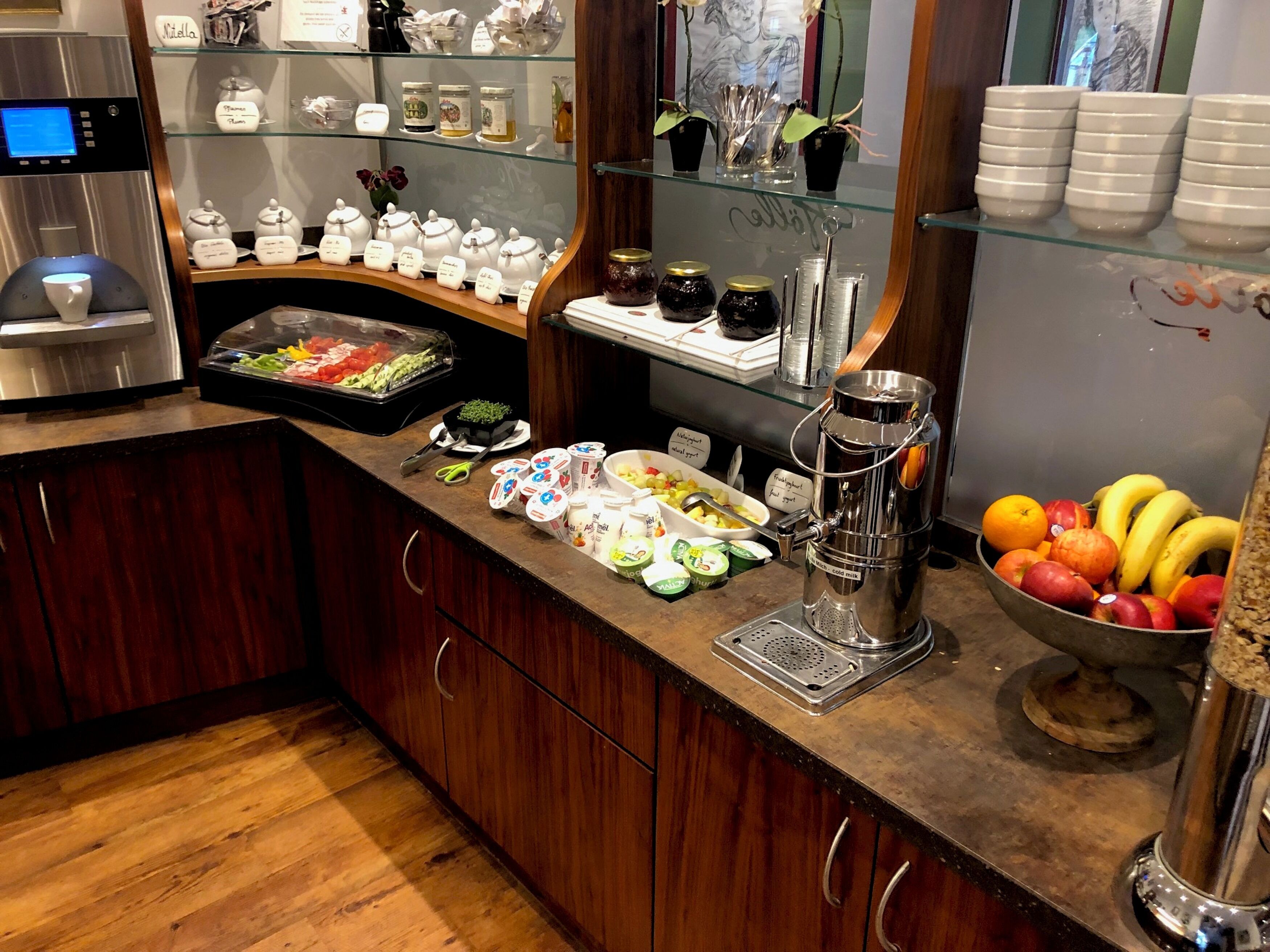 A breakfast bar with a coffee machine, a fruit bowl, and various condiments.