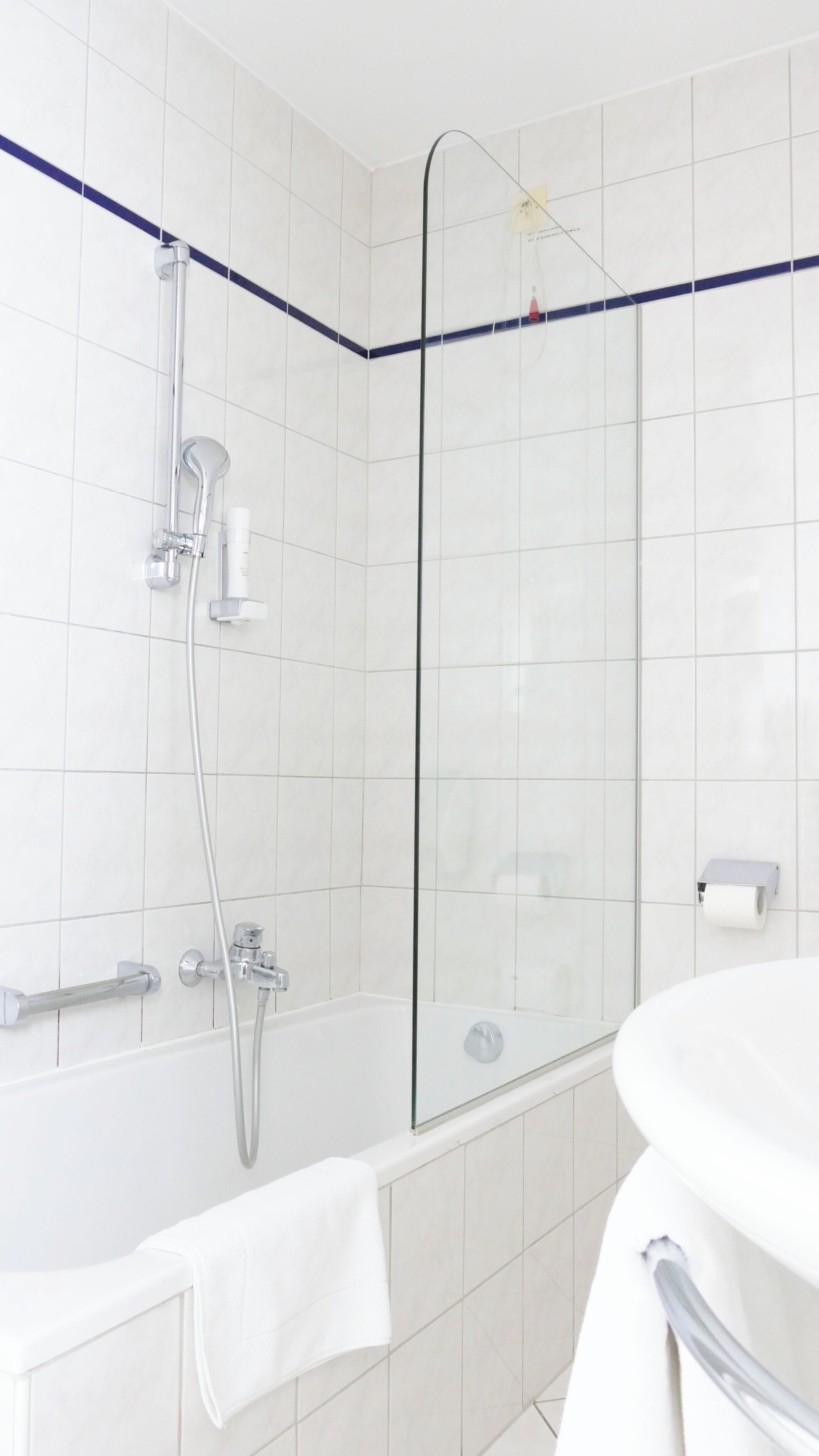 Un baño moderno con cabina de ducha de vidrio, una bañera blanca y un lavamanos blanco.
