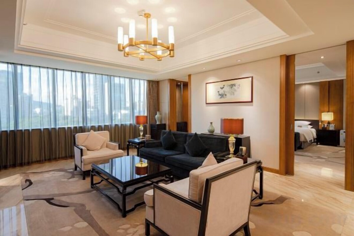 Habitación de hotel con sala de estar, sofá, mesa de centro y candelabro.