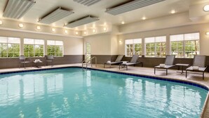 An indoor swimming pool with clear blue water, surrounded by lounge chairs and a view of trees through large windows. - Residence Inn by Marriott Houston Northwest/Willowbrook. (Houston)