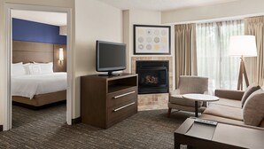 A hotel room with a bed, a TV, a fireplace, a sofa, and a coffee table. - Residence Inn by Marriott Houston Northwest/Willowbrook. (Houston)