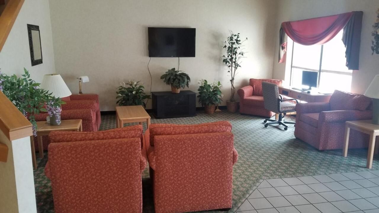 A living room with a sofa set, a TV, and potted plants.