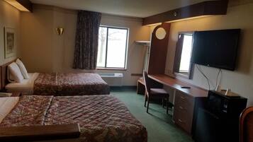A hotel room with two beds, a desk, a chair, a television, and a refrigerator.