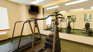 Un gimnasio con cintas de correr, una bicicleta estática y un espejo.