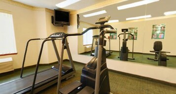 Un gimnasio con cintas de correr, una bicicleta estática y un espejo.