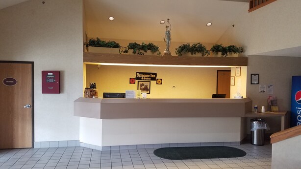 Zona de recepción de un hotel con mostrador, puerta a sala privada, un bote de basura y un letrero de Pepsi.