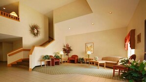 Un salón espacioso con una escalera, un sofá, una mesa de centro y una chimenea.
