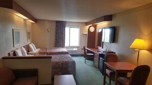 Una habitación de hotel con cama, escritorio, silla, sofá y televisión.