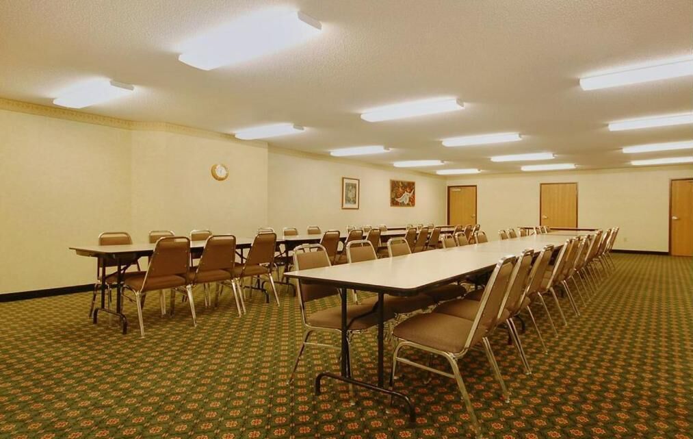 A conference room with a long table and multiple chairs, carpeted floor, and ceiling lights.