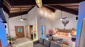 A spacious living area with a grey sofa, a dining table, and a kitchen area visible through an open door.