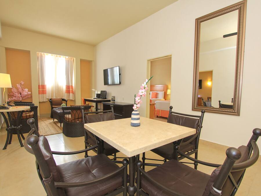 A dining area with a table and chairs, a television, and a mirror on the wall.