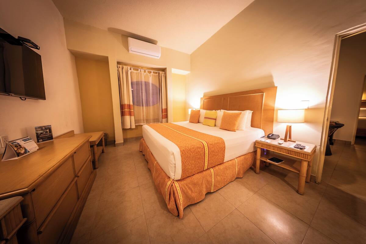 Ein Hotelzimmer mit Bett, Nachttisch, Lampe und Schreibtisch mit Stuhl.