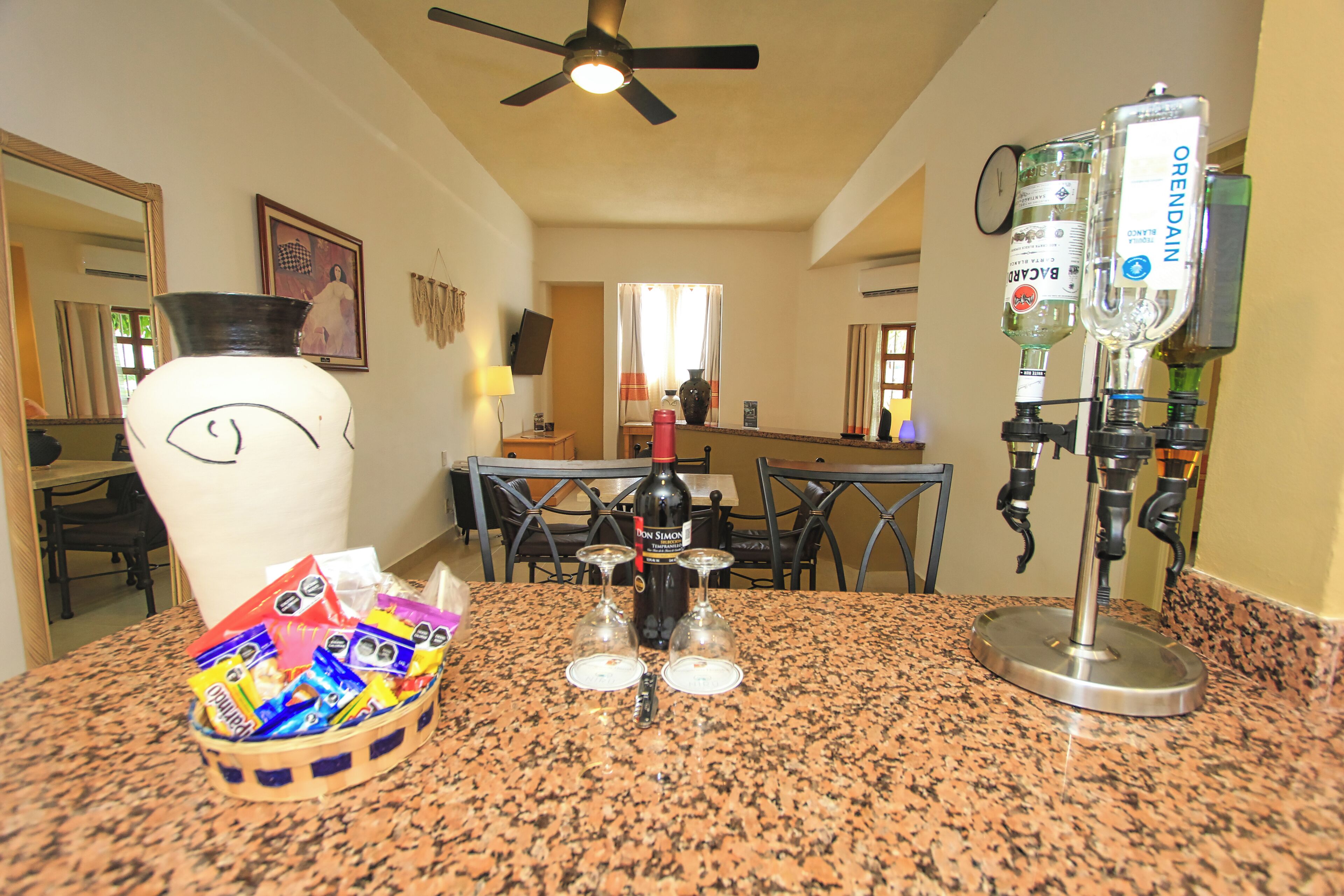 A kitchen counter with a coffee maker, wine glasses, and a bottle of wine.