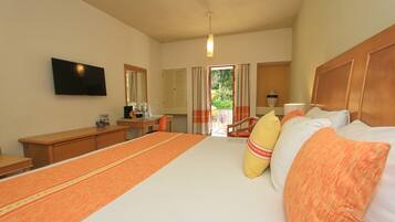 A hotel room with a large bed, a desk, a chair, a television, and a window with curtains.