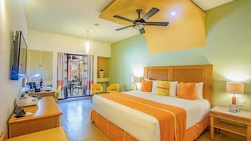 Une chambre d’hôtel avec un grand lit, un bureau, une chaise, un ventilateur de plafond et une vue sur l’extérieur.