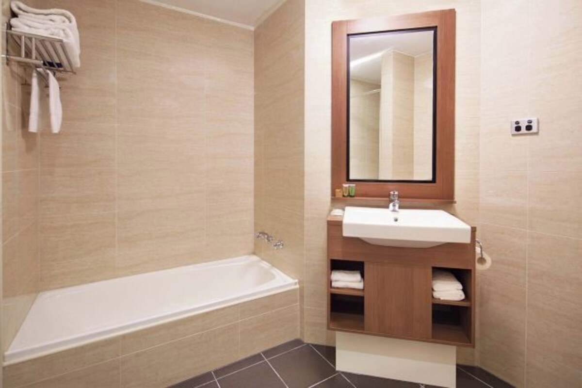 Une salle de bain moderne avec une baignoire, un lavabo et un miroir.