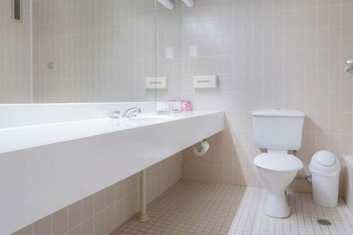 A bathroom with a white sink, toilet, and tiled walls.