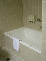 A bathroom with a white bathtub, beige tiles, and a towel hanging on the side.