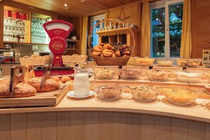 Een ontbijtbuffet met diverse broden, gebakjes en bakken met ontbijlgranen.