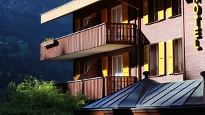 Een hotel met een houten gevel, balkons en uitzicht op de bergen.