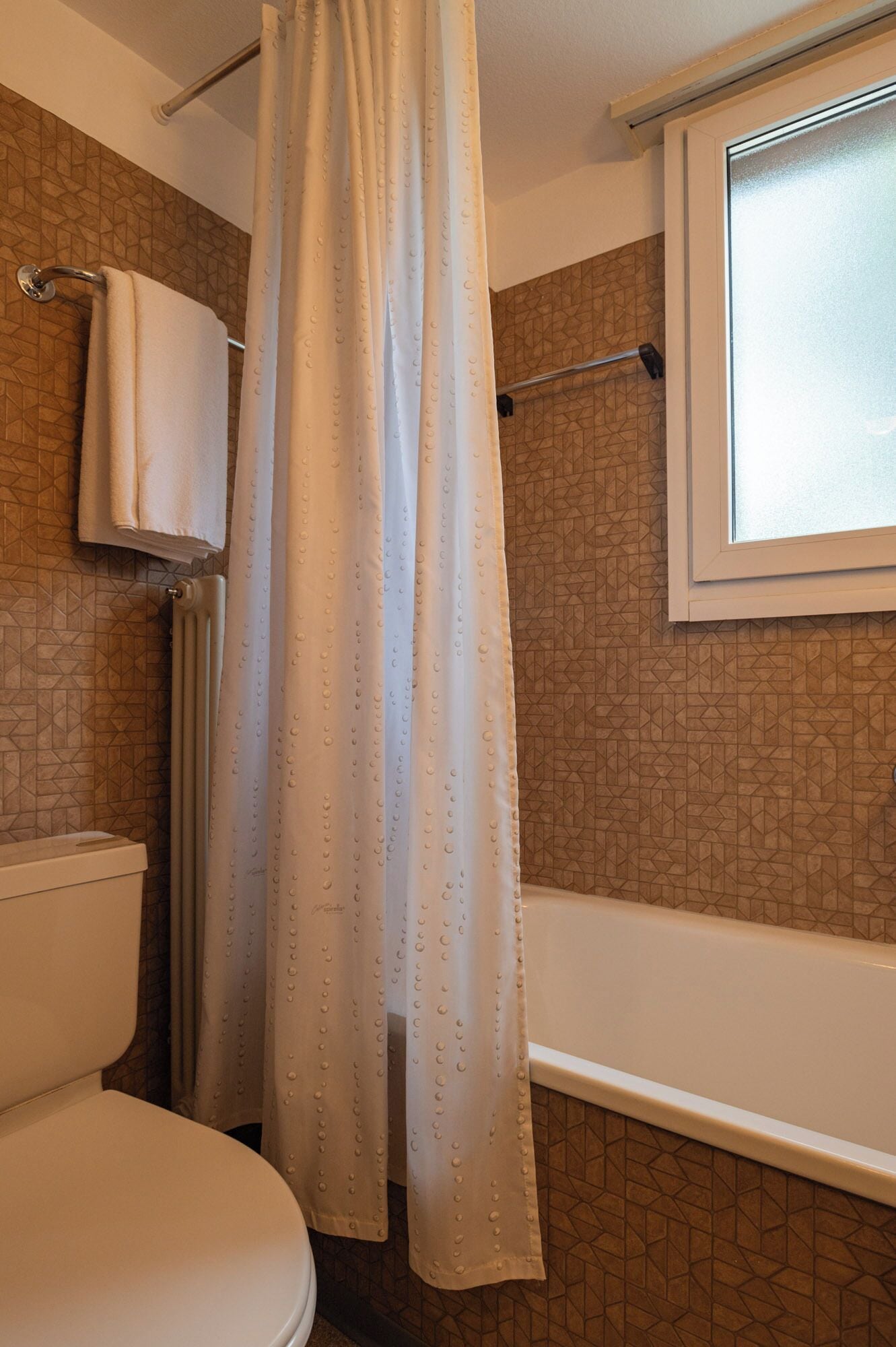 A bathroom with a shower curtain, a toilet, and a bathtub.