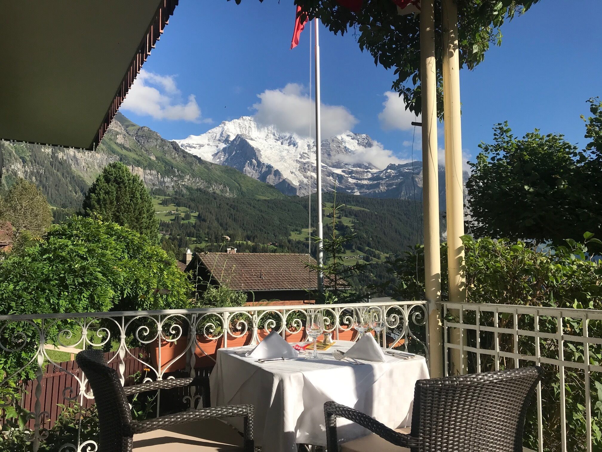 Una terraza con mesa y sillas, con vistas a un paisaje montañoso y cumbres nevadas.