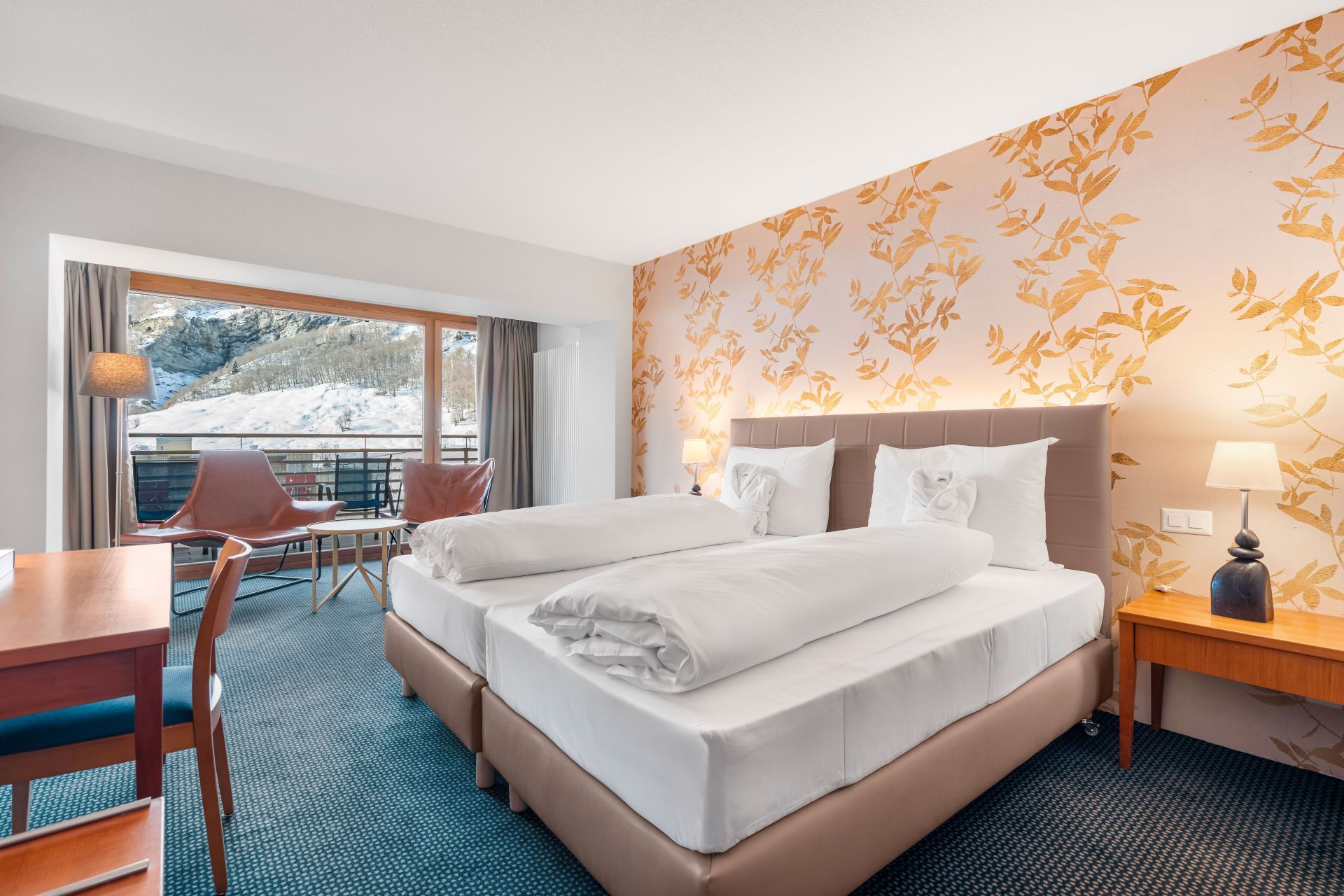 Una habitación de hotel con cama, escritorio, silla y vista a un paisaje nevado.