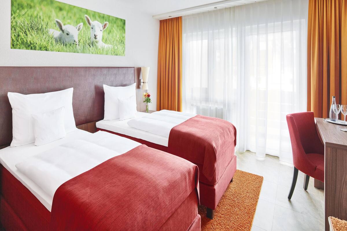 Ett hotellrum med två sängar, ett skrivbord och en stol.