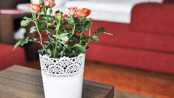 A white vase with a lace pattern containing three roses on a wooden table.