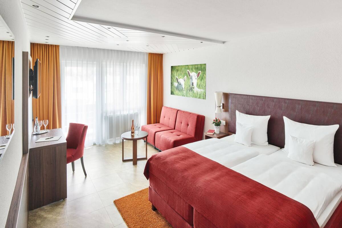 Ett hotellrum med en stor säng, ett skrivbord, en stol och ett litet bord.
