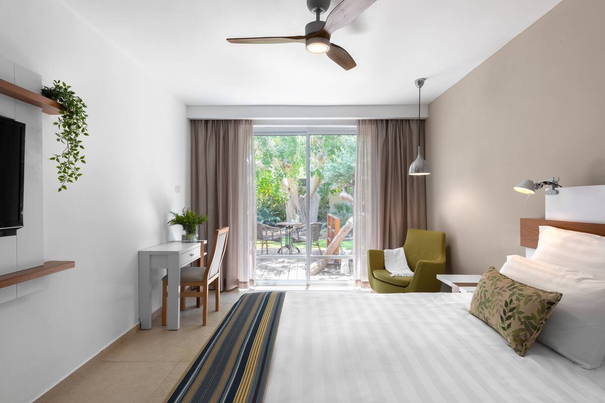 Une chambre d’hôtel moderne équipée d’un lit, d’un bureau, d’une chaise et offrant une vue sur l’extérieur.