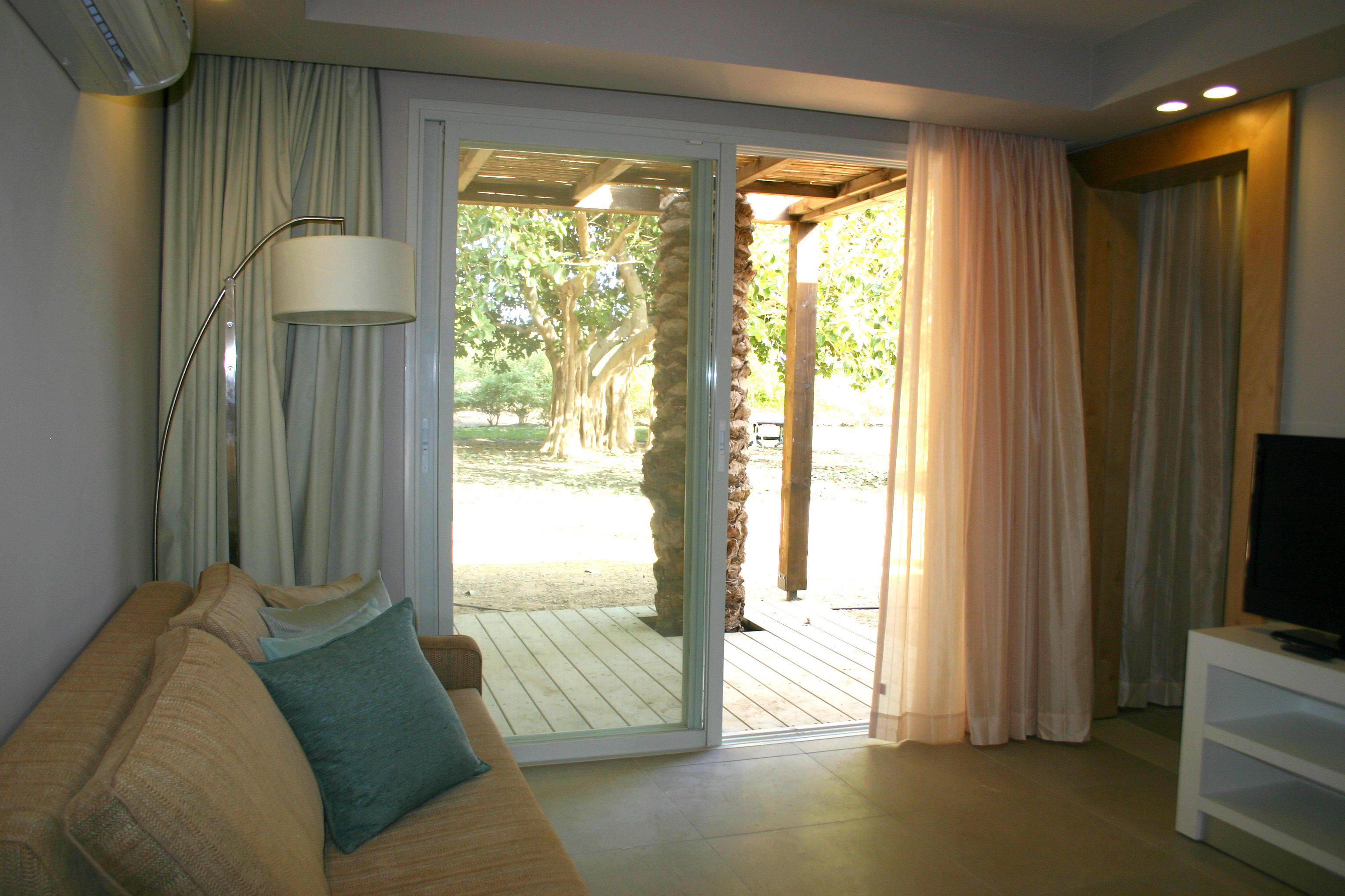 A living room with a sofa, a TV, and a sliding glass door leading to an outdoor area.