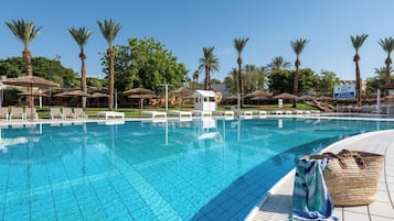 Una piscina techada, una piscina al aire libre, sombrillas