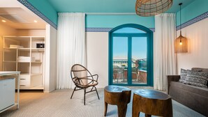 A modern room with a view to the outside, a wicker chair, a small table, and a sofa. - U Splash Resort Hotel Eilat (Hevel Eilot)