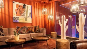 A modern living room with a sofa, two side tables, a cactus, and a large abstract painting on the wall. - U Splash Resort Hotel Eilat (Hevel Eilot)