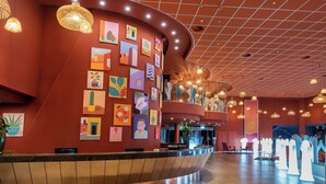 A hotel lobby with a curved reception desk, artwork on the walls, and hanging pendant lights. - U Splash Resort Hotel Eilat (Hevel Eilot)
