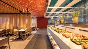 A modern restaurant interior with wooden slat partitions, a buffet with various food items, and a ceiling with a geometric pattern. - U Splash Resort Hotel Eilat (Hevel Eilot)