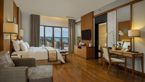 Habitación de hotel con cama, escritorio, silla, televisión y vista al océano.
