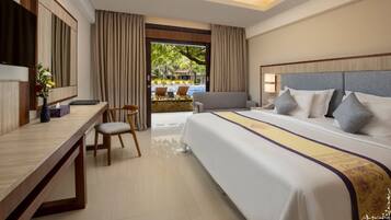 A hotel room with a large bed, a desk, and a view of an outdoor pool area.