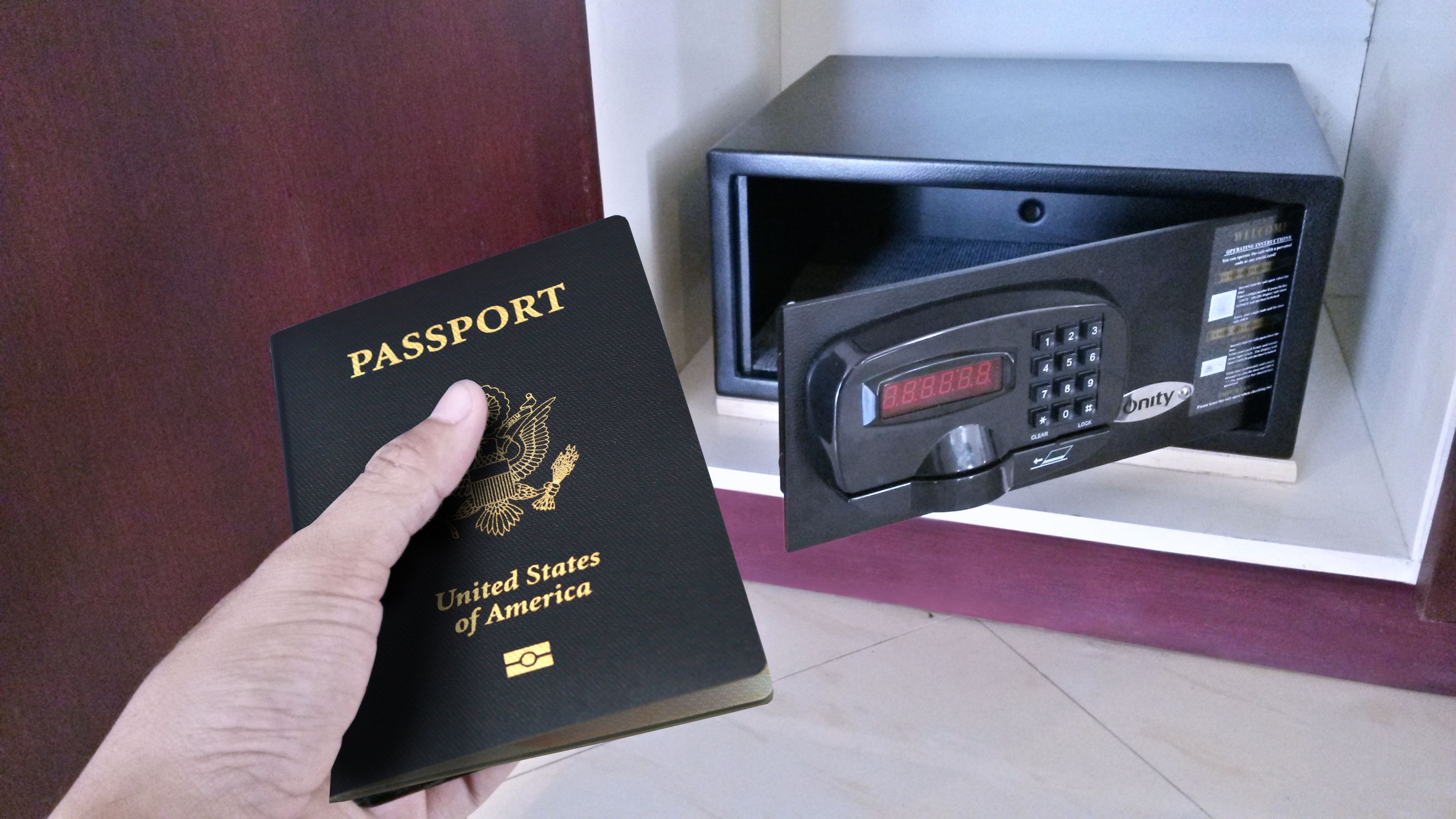 A hand holding a United States passport, a safe, and a keypad lock.