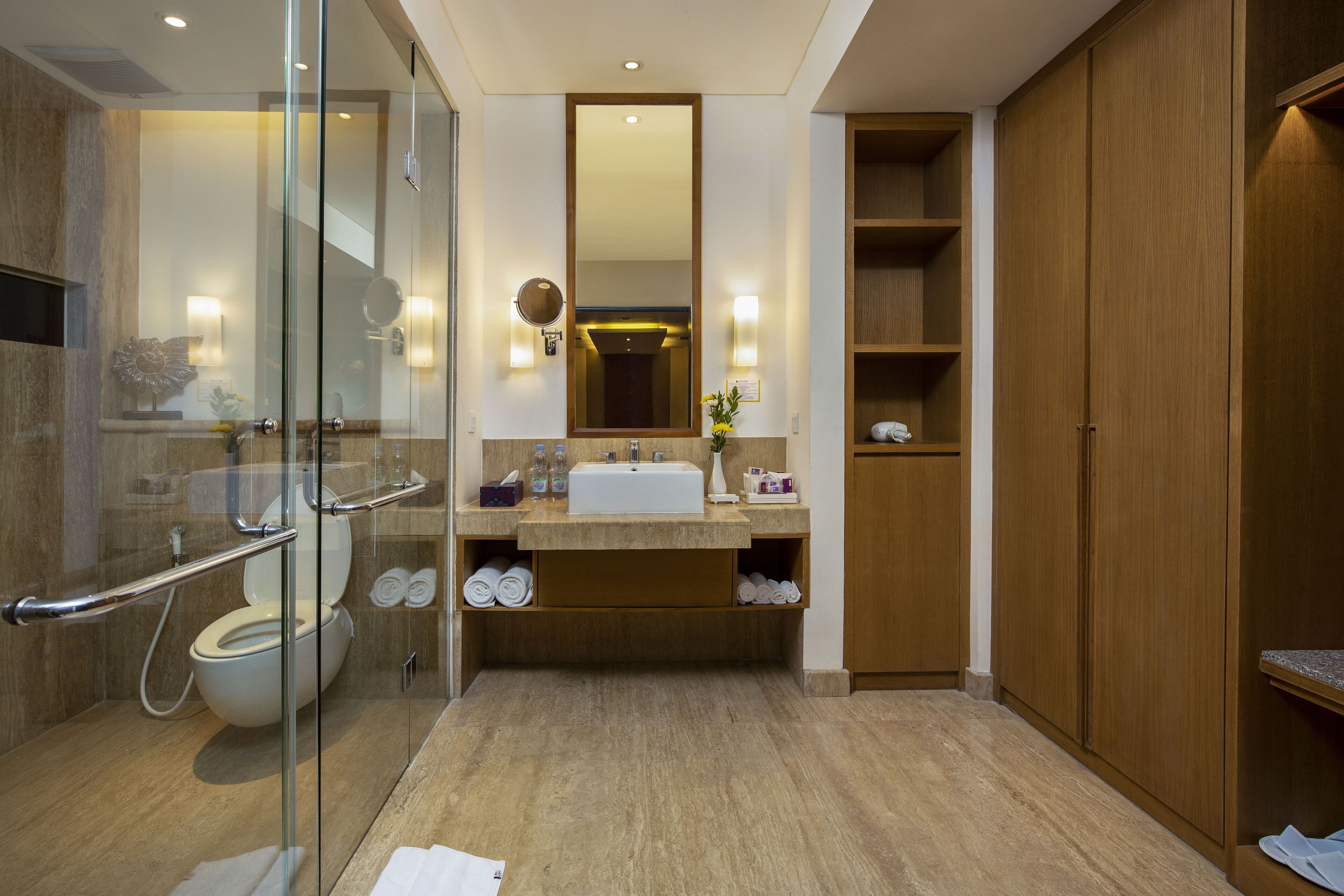 Une salle de bain moderne avec une douche à l’italienne en verre, un lavabo avec un miroir au-dessus et des étagères en bois.