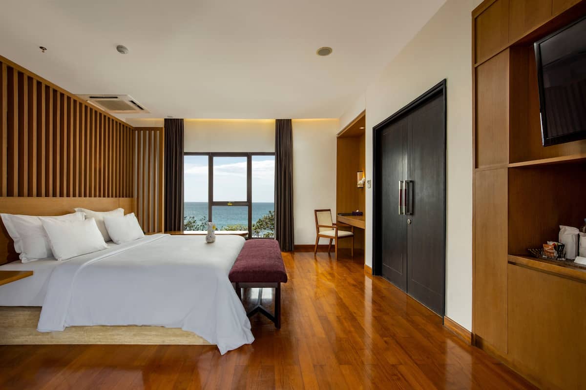 A modern bedroom with a large bed, a desk, and a wardrobe.