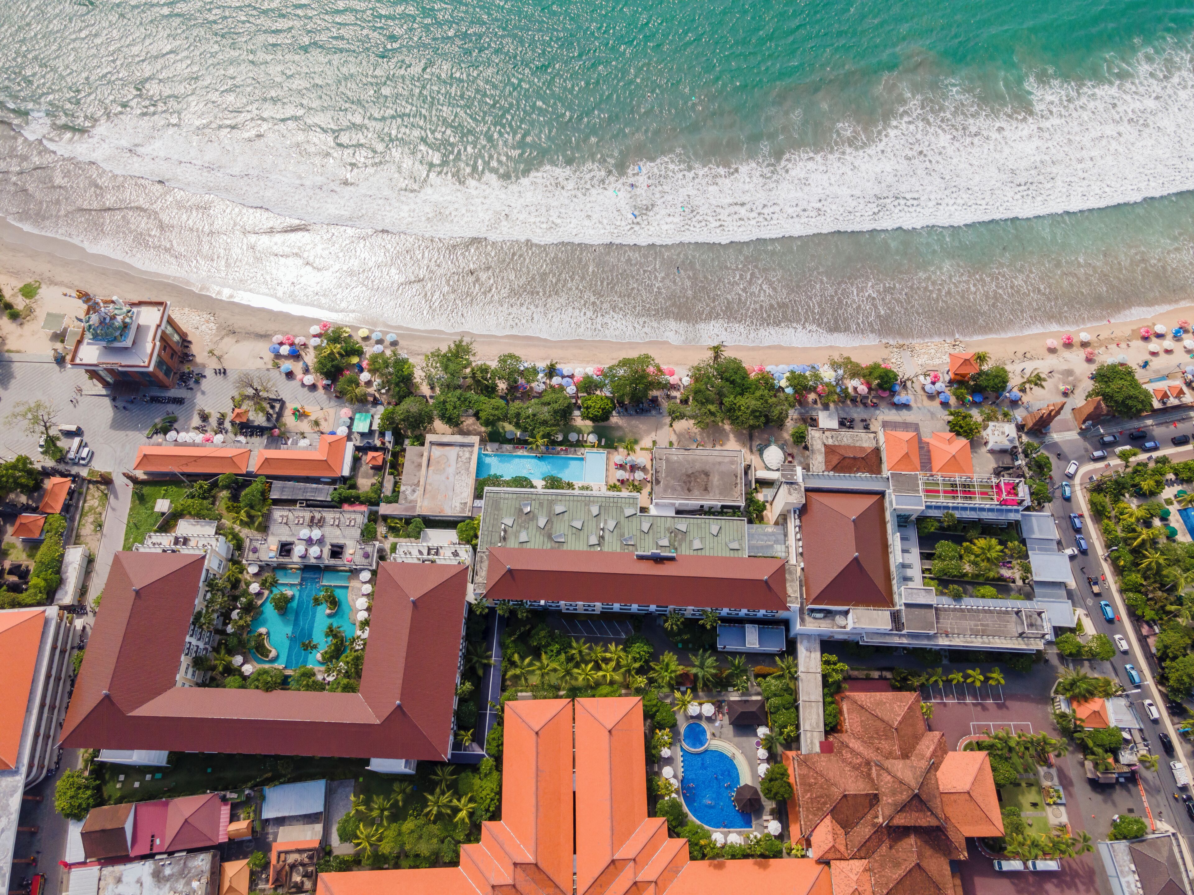 Vista aérea de un resort con varias construcciones, una playa y una piscina.